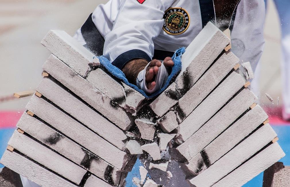 Geste d'un karateka détruisant de sa main un empilement de briques