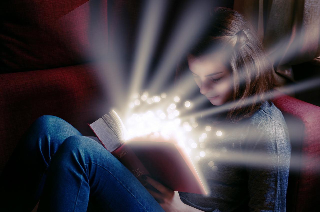 De profil, une jeune fille tient un livre ouvert sur ses jambes repliées devant elle. Durant sa lecture, des raies de lumières et des étoiles éblouissantes sortent du livre pour éclairer son visage.