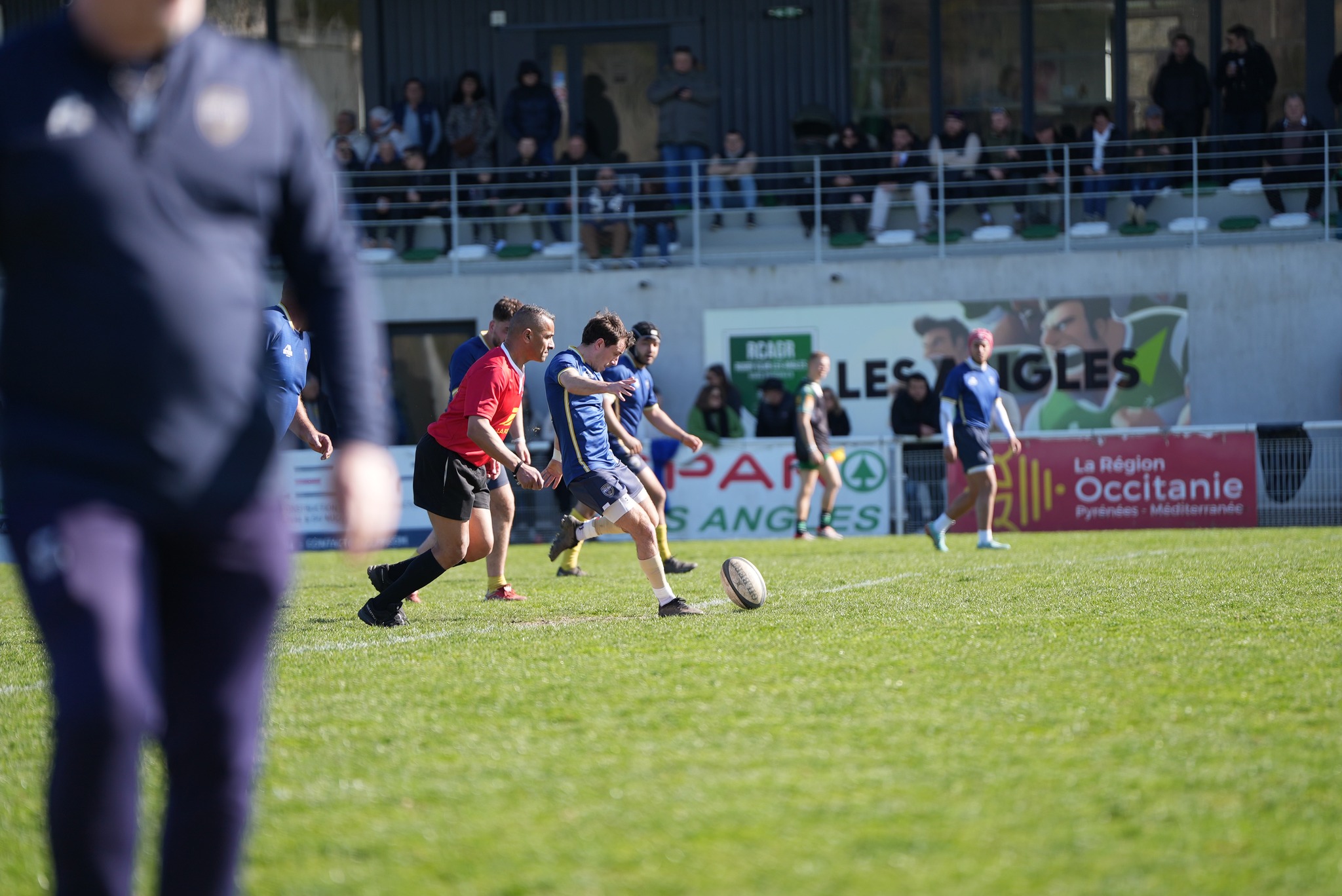 Durant un match de rugby, un joueur est en train de taper une pénalité; c'est-à-dire qu'il est en train de taper du pied dans un ballon disposé sur un tee (support de frappe) pour l'envoyer entre les poteaux. Ce joueur, pris en photo durant sa course, frappe du pied gauche, les yeux fixés sur le ballon, le corps incliné en diagonale.